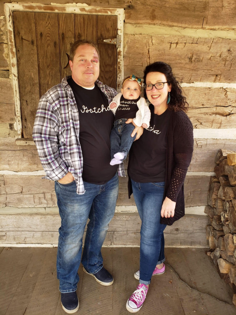 mom dad and baby girl taking a picture outside their house