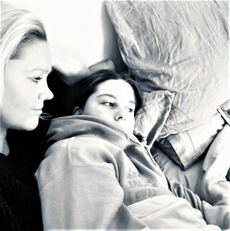 black and white image of a mom laying in bed with her teenage daughter 