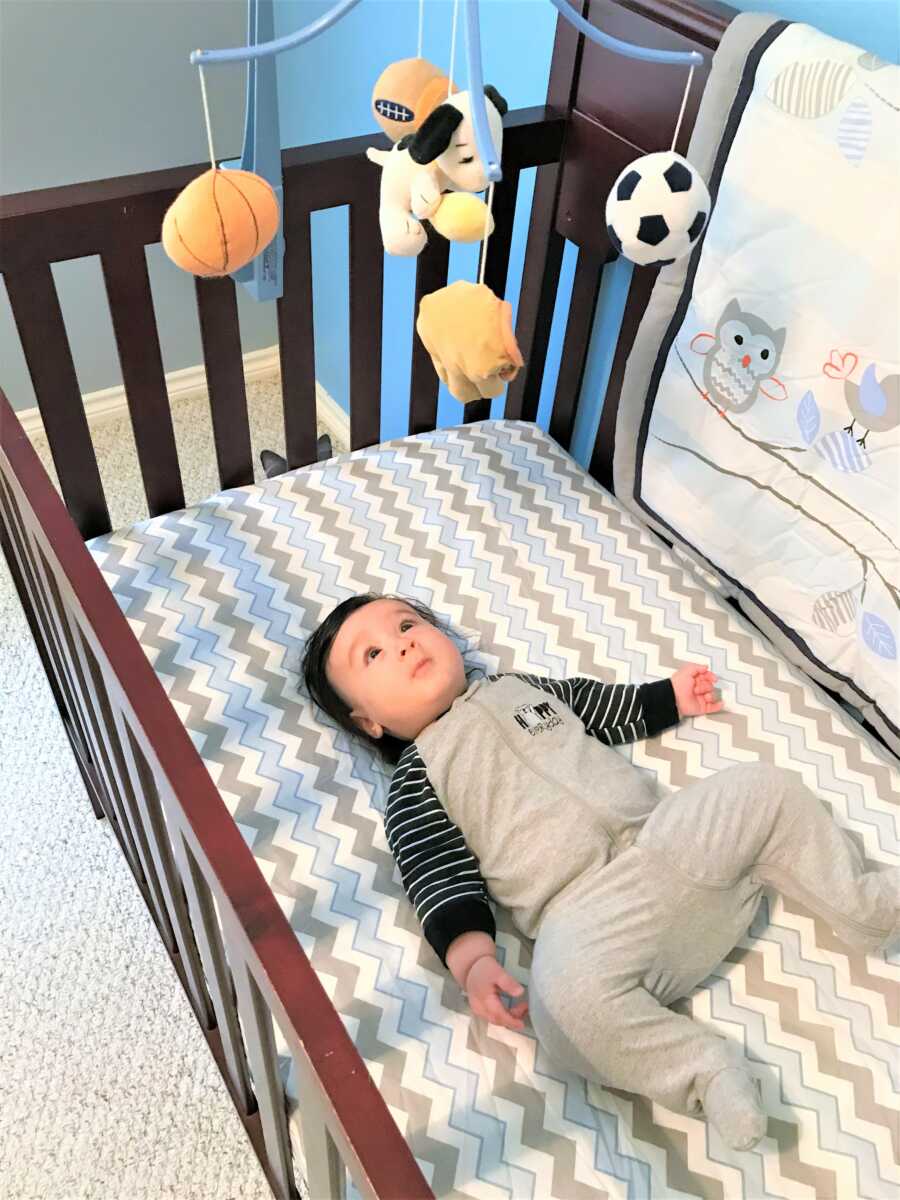 baby boy laying on his back on his crib 