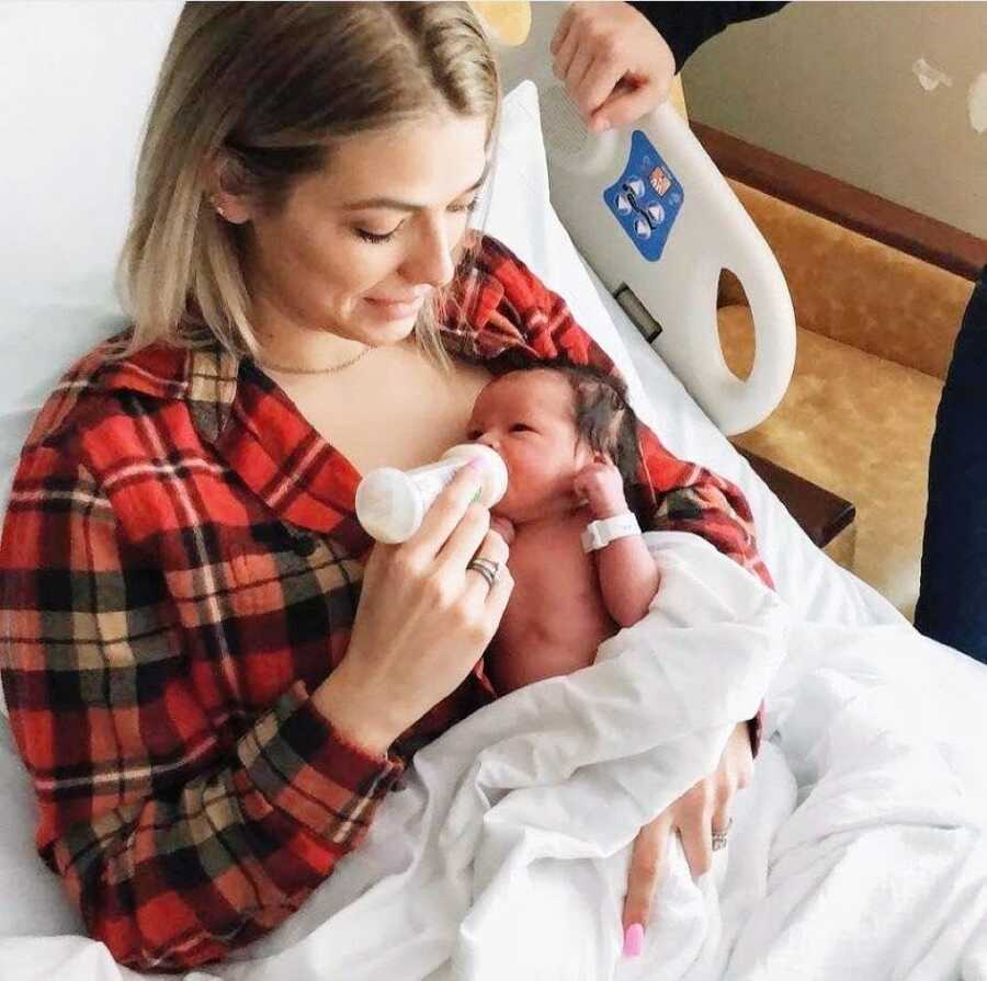 Woman bottle feeds newborn adoptive daughter