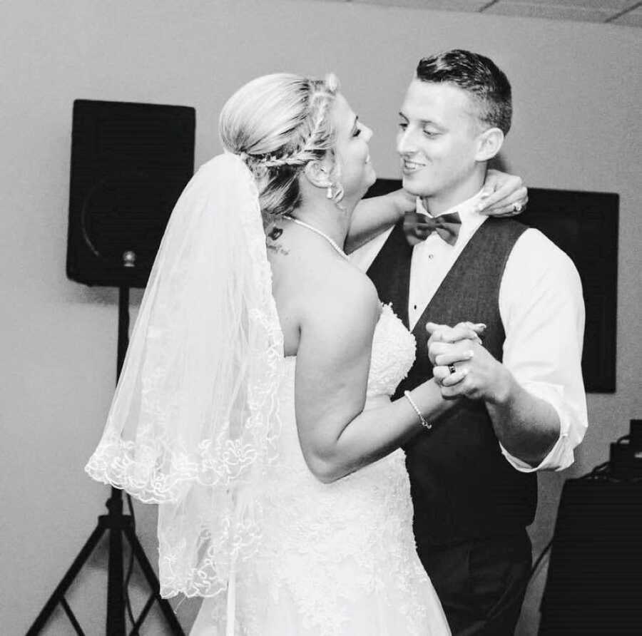 Newlyweds dance together at their wedding while smiling at one another