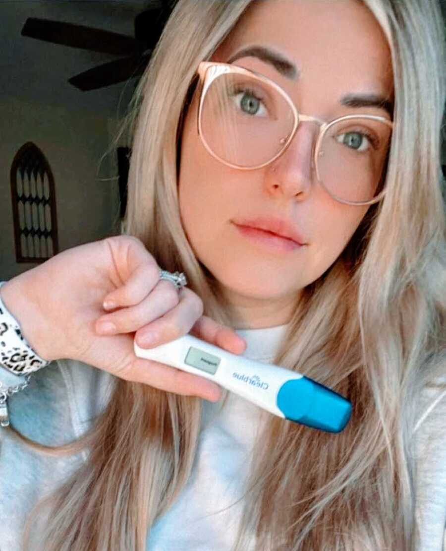 Woman battling infertility through IVF takes a selfie with a positive pregnancy test