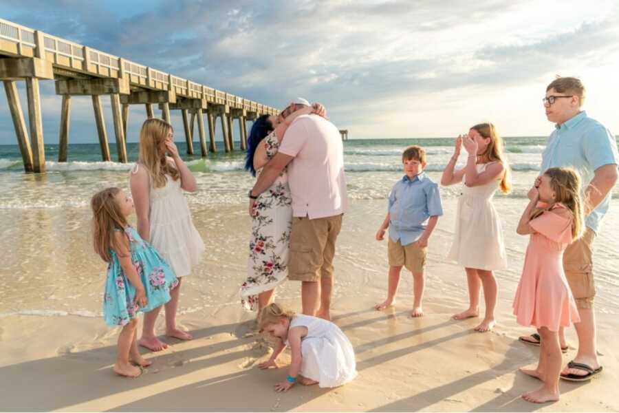 husband and wife getting married on a beach with family