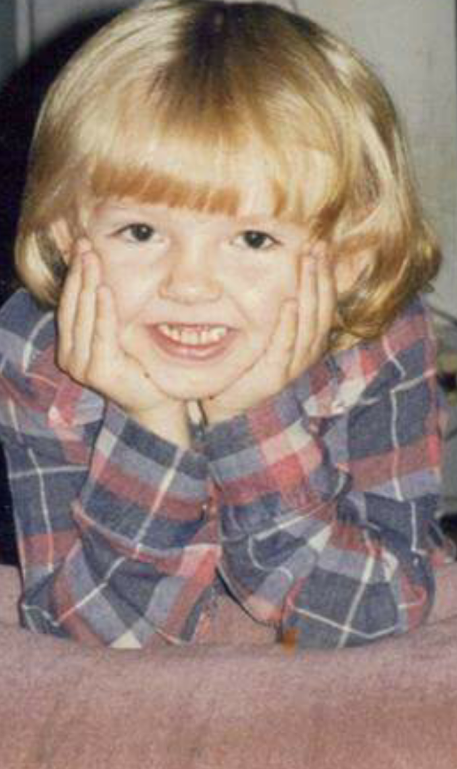 little girl smiling with her head in her hands