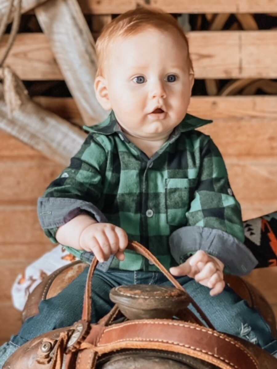 son on a saddle holding the reigns