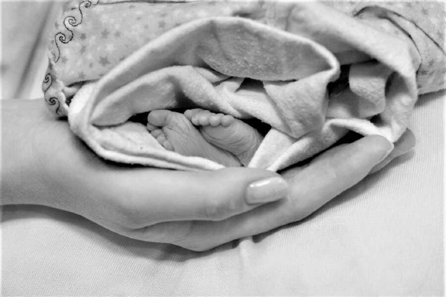 close up of the feet of a stillborn baby being held by his mother 