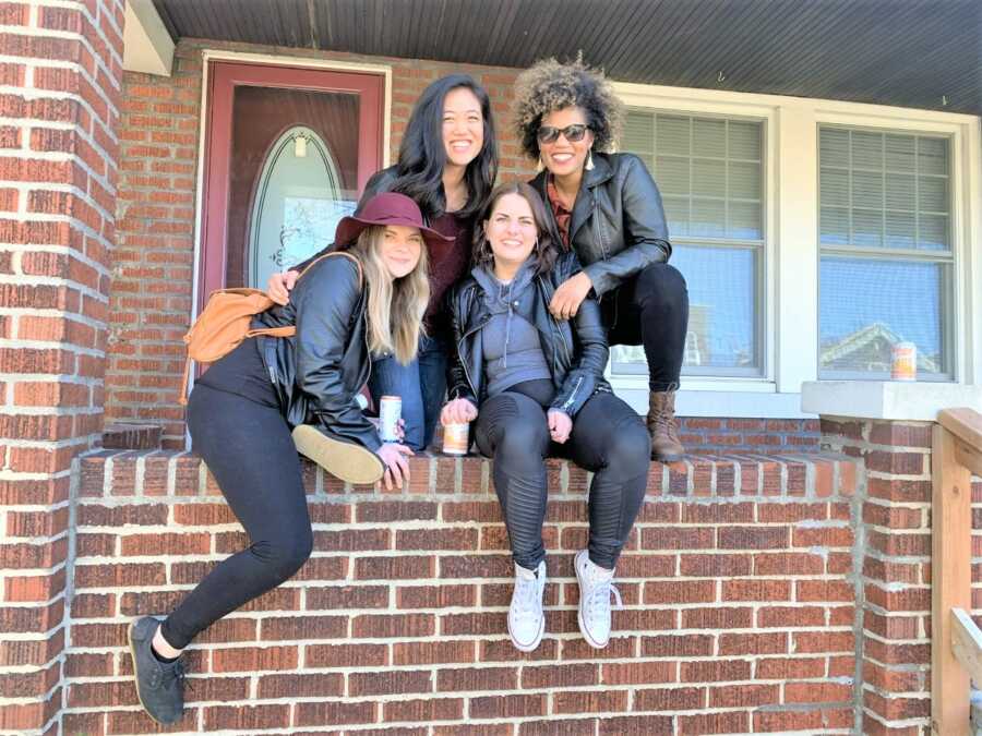 Group of four girl friends sitting in the entrance of a house