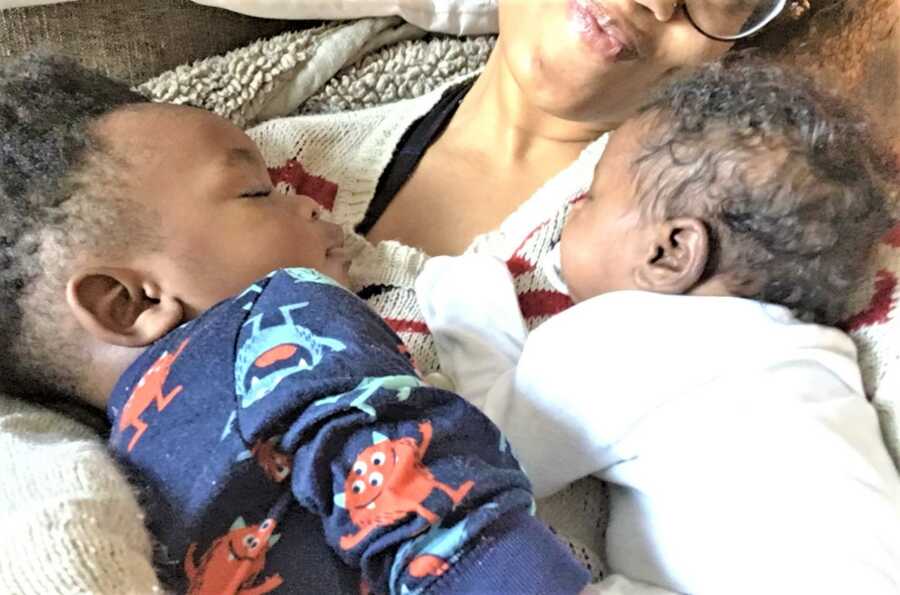 Black woman taking a nap with two young children resting on her chest 