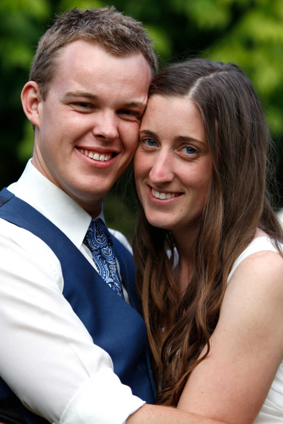 Young couple smile ate camera for close up on wedding day.