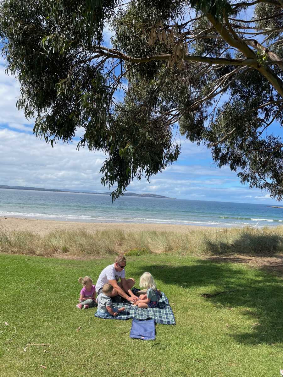 Foster family has picnic in grassy area next to the beach.