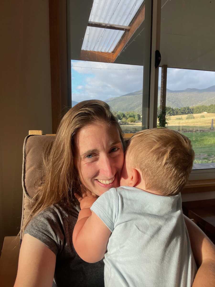 Foster mom holds young boy in her arms as she sits in a rocking chair.