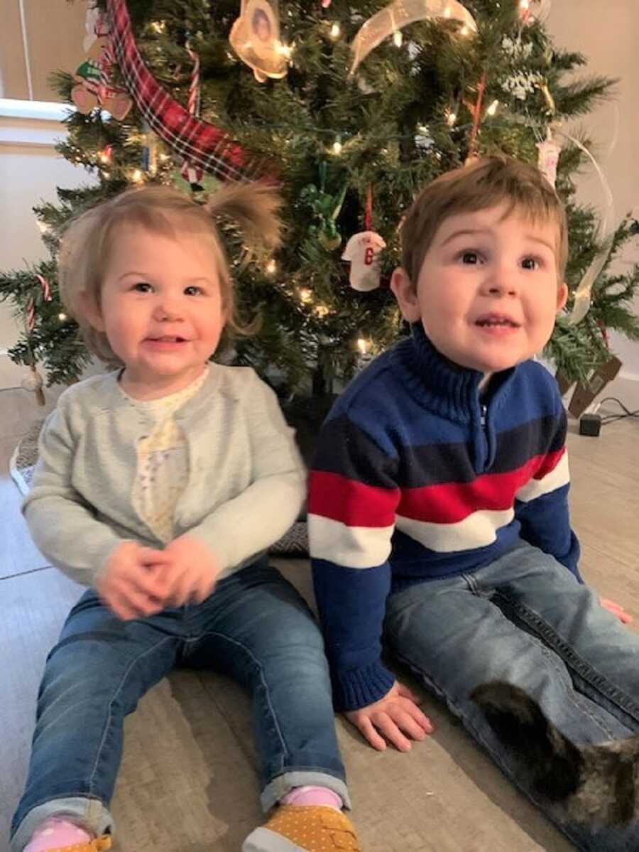 Foster siblings sit next to each other in front of a Christmas tree.