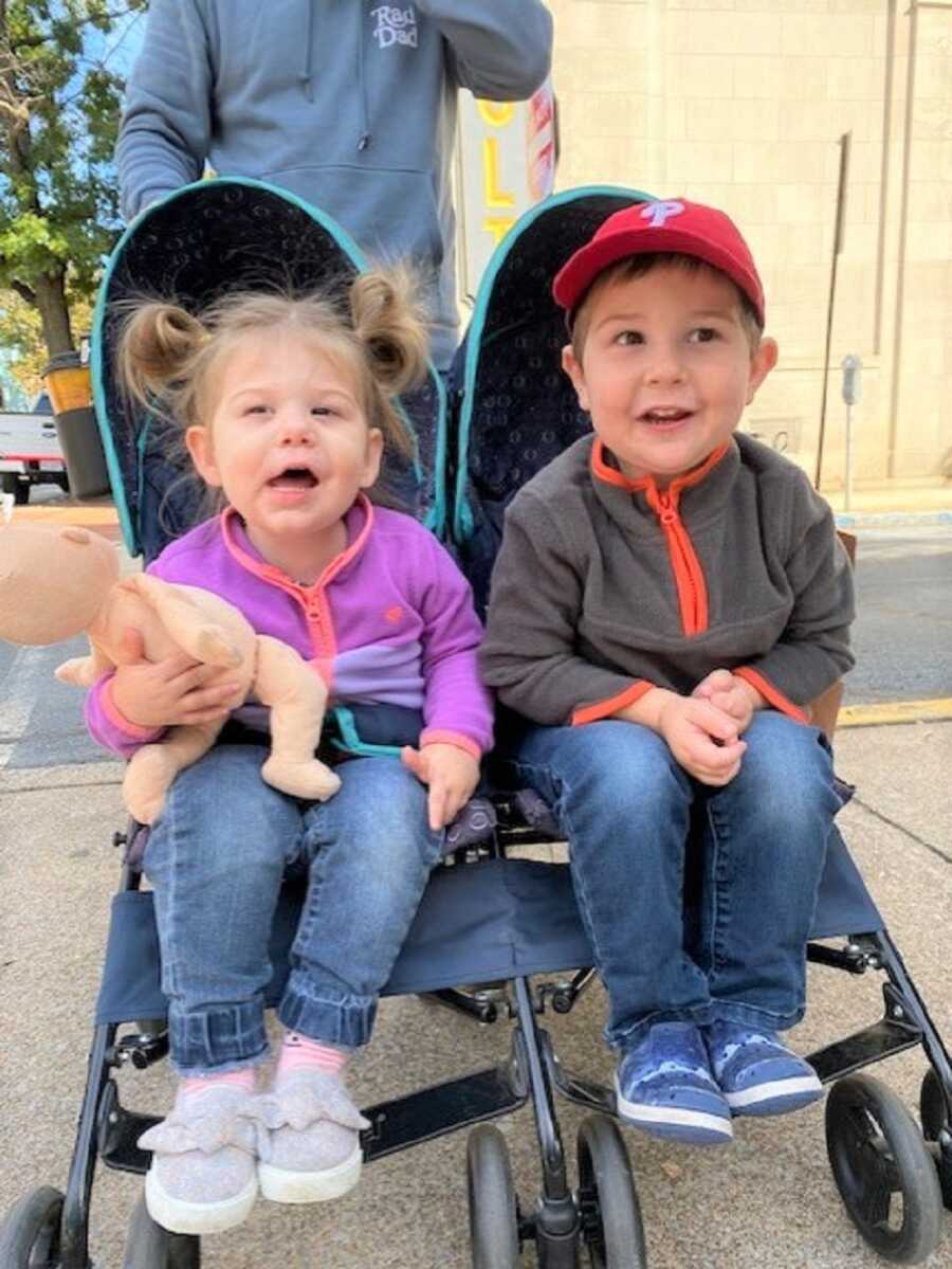 Siblings in foster care sit in double stroller together.