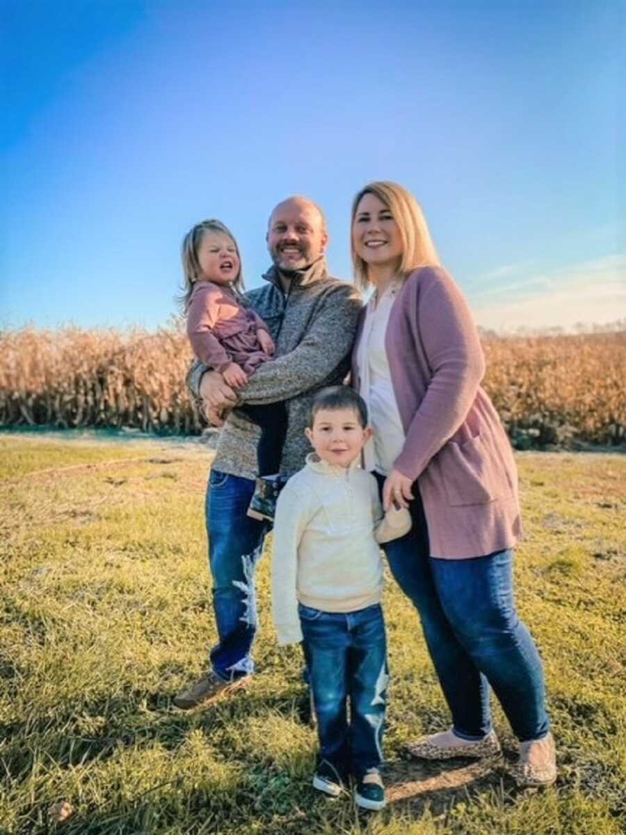 Couple takes outdoor family picture with two young children.