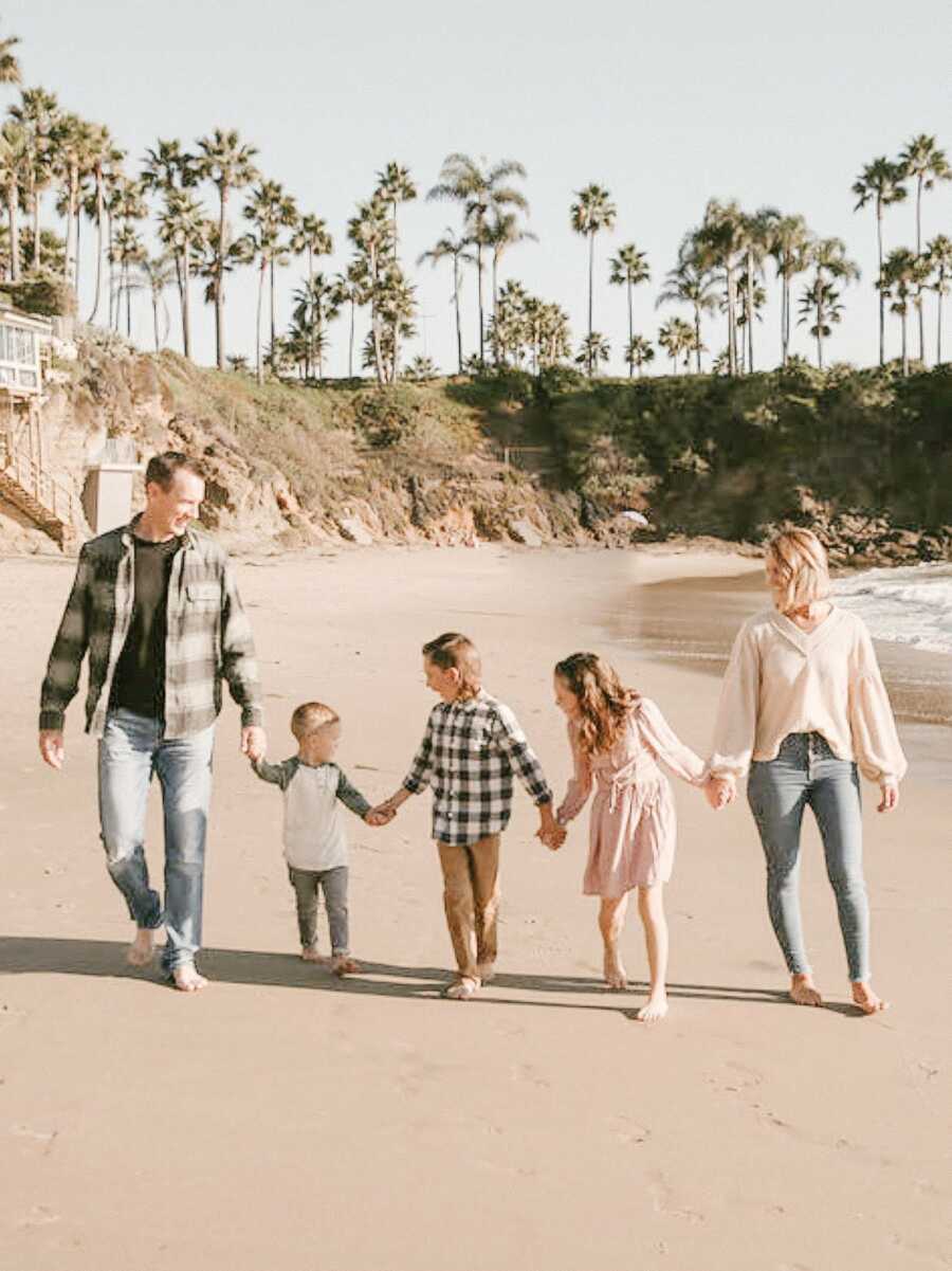 family holding hands taking pictures on the beach