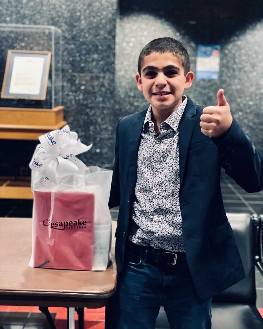 A boy gives a thumbs up after giving a speech to the city council