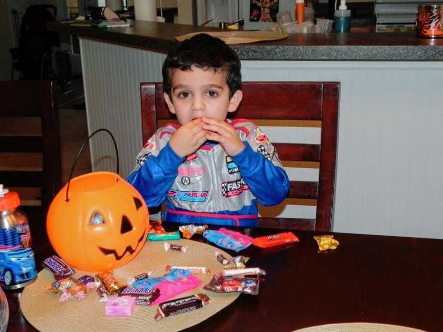 A little boy sitting at a table with Halloween candy