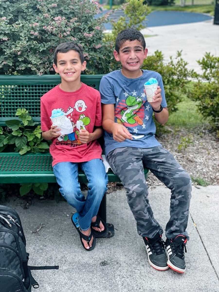 A boy sitting with his brother on a park bench