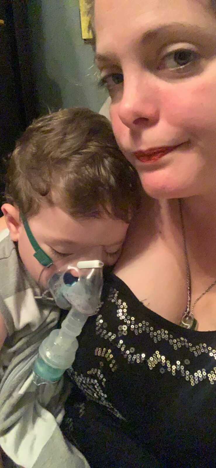 son with mask on laying on mom