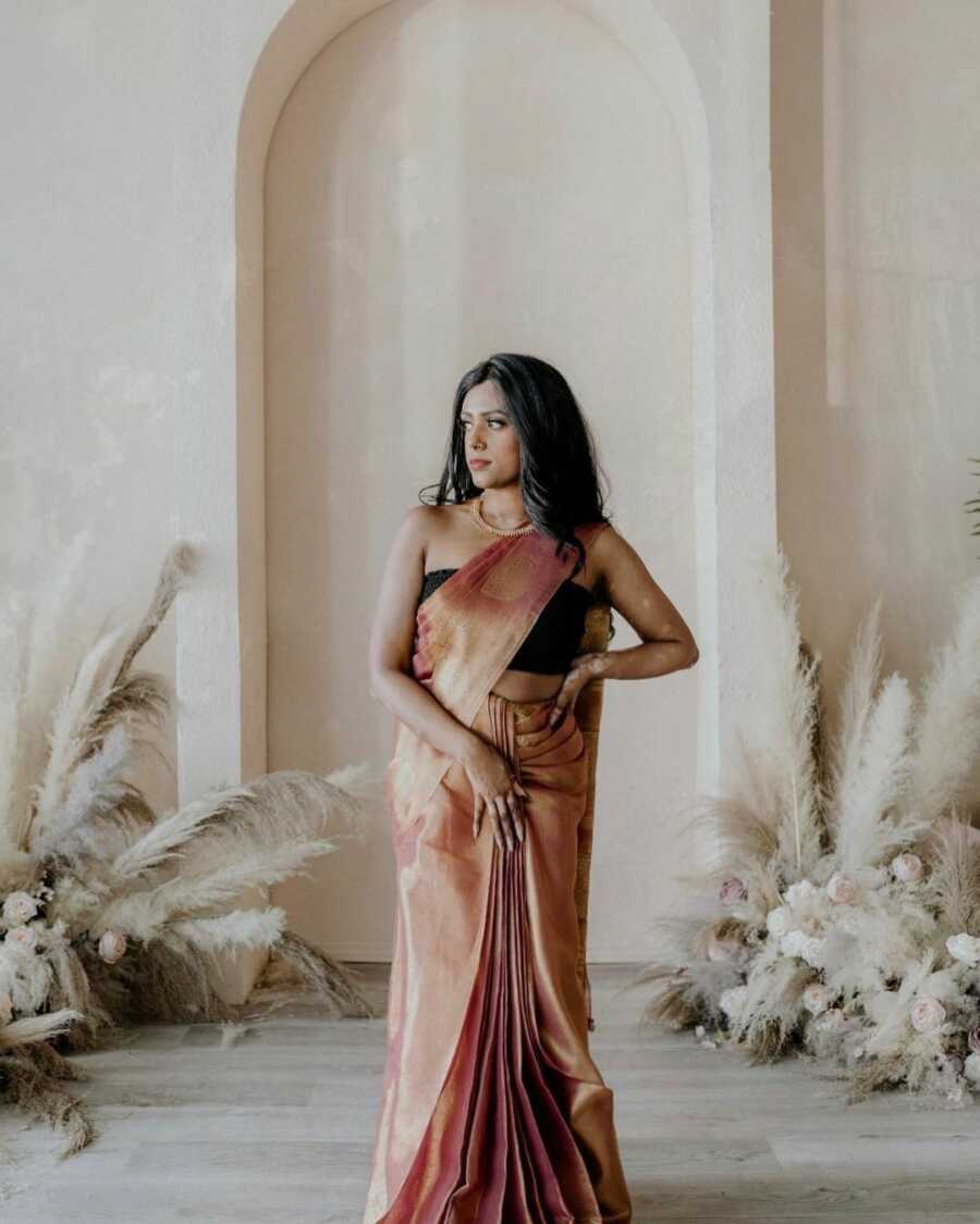 woman with vitiligo poses elegantly in a room with flowers and feathers