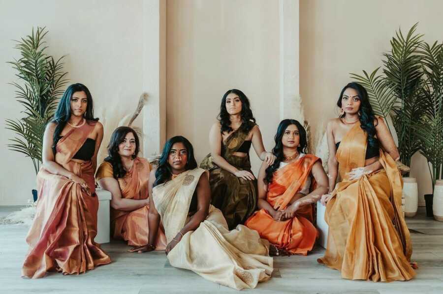 group of women with vitiligo sit lined up next to each other, dressed elegantly in traditional clothing