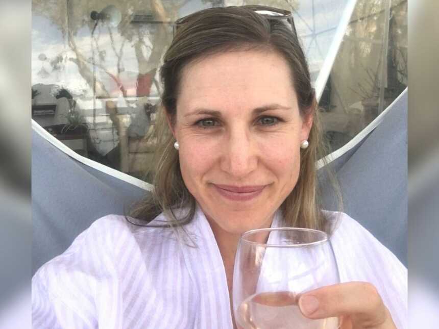A mom holding a glass of wine sitting outside
