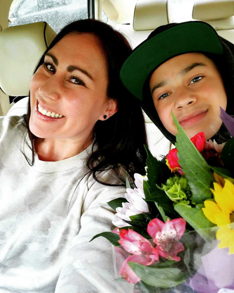 sober woman takes a selfie in the car with her son with flowers