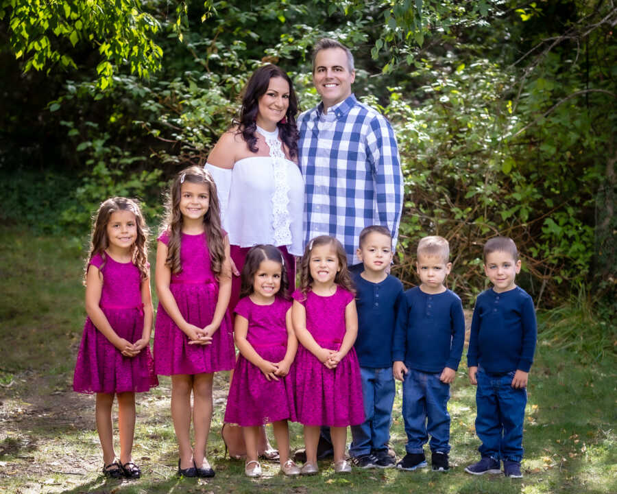 family, including mom, dad, two older children and quintuplets stand together all smiling