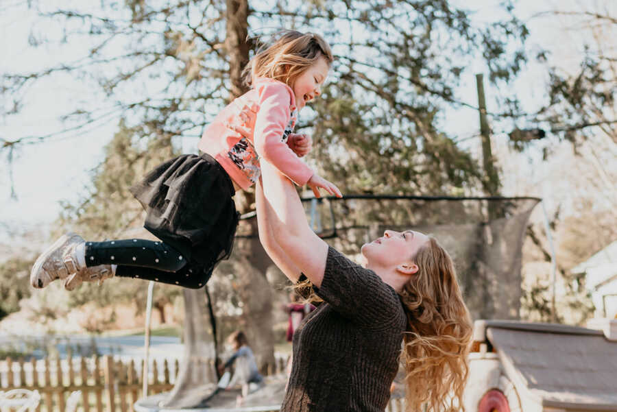 A young girl being held up by her biological aunt