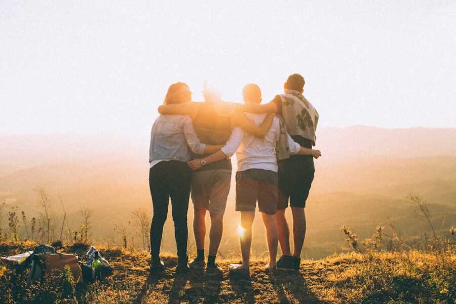 group of four friends stands together looking over horizon