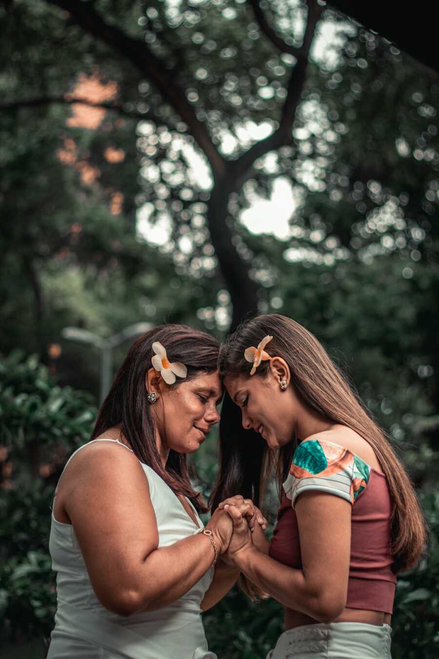 mother and daughter hold hands and put their foreheads together