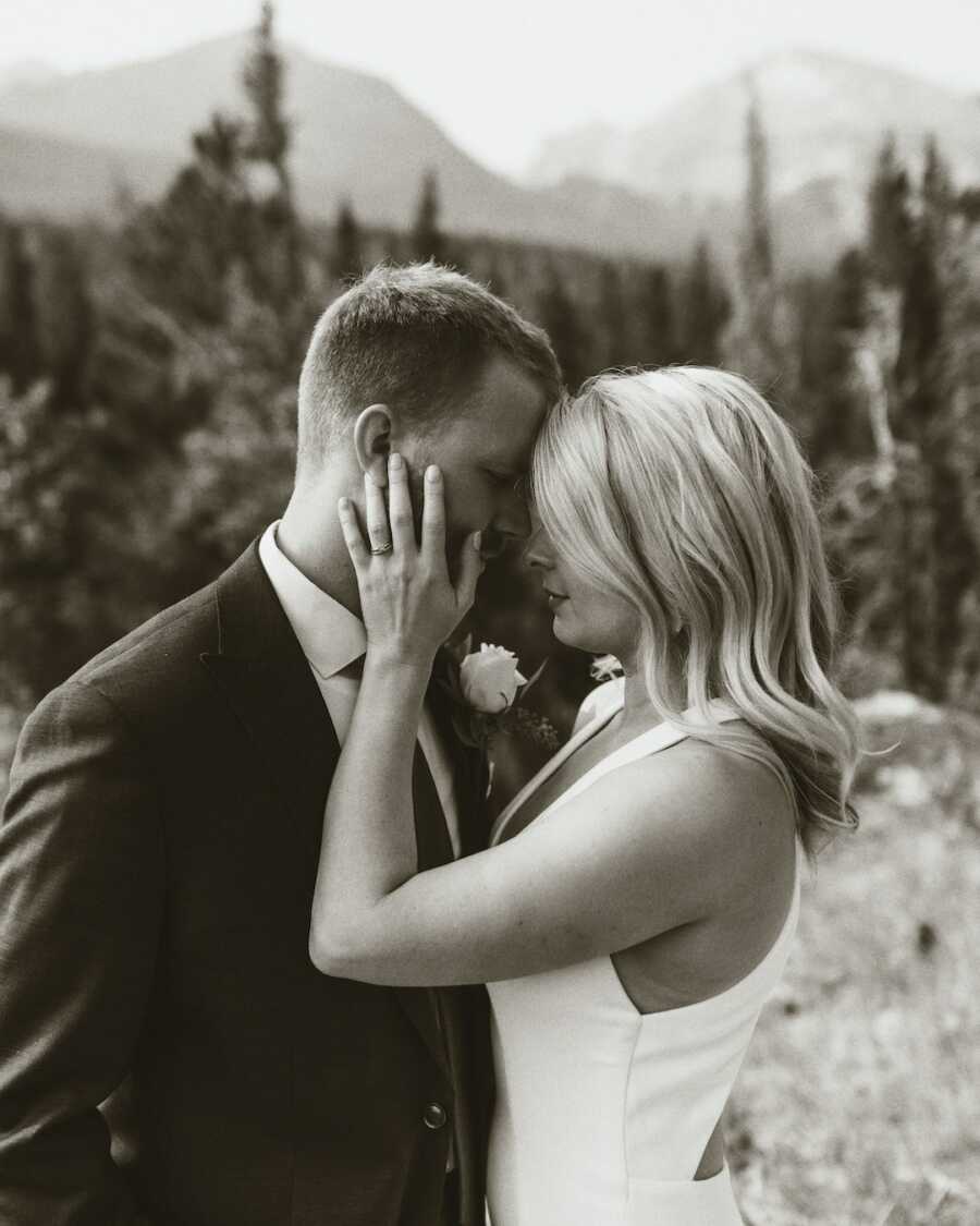 husband and wife stand with their foreheads touching one another