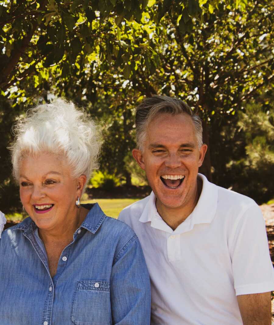 older married couple sit next to each other smiling