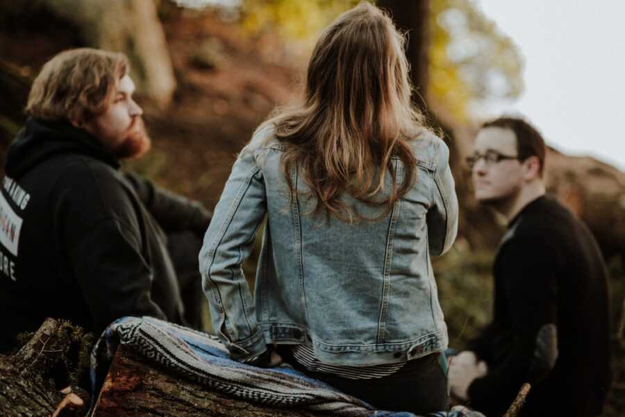 three friends sit together in the woods