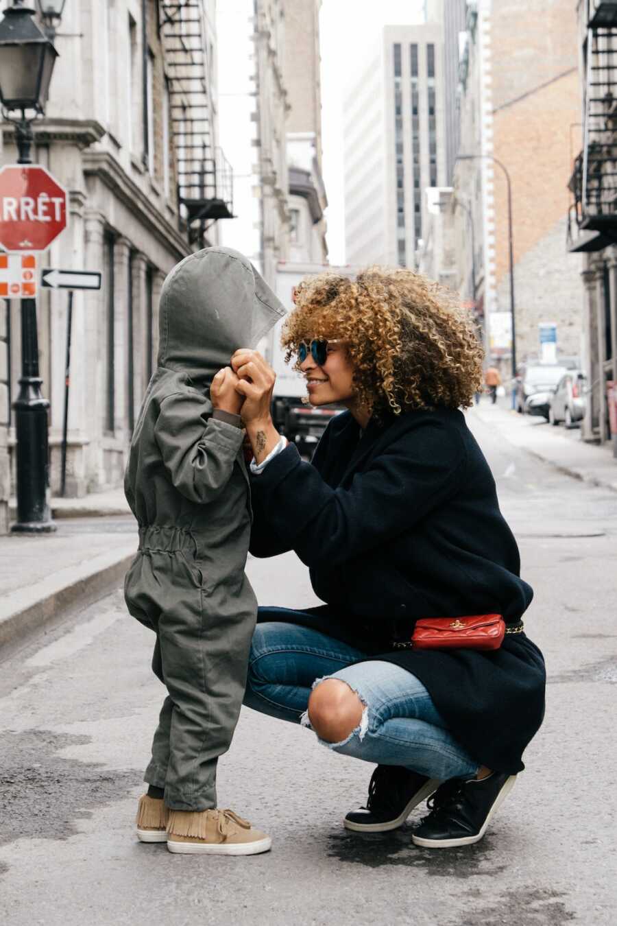 mom holds her child's hands and bends to their level