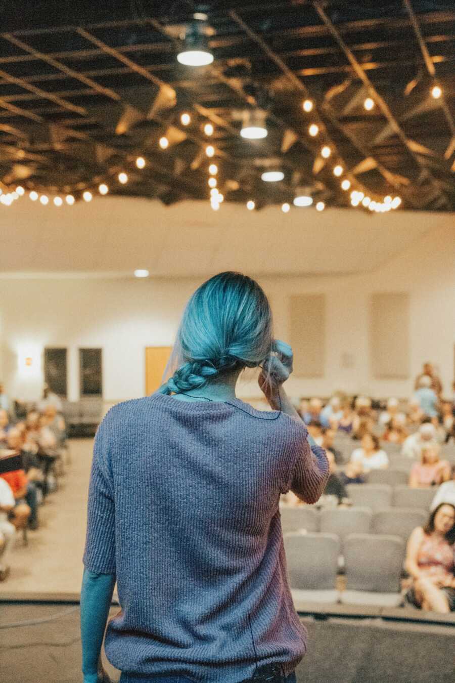 woman stands in front of a crowd in an auditorium