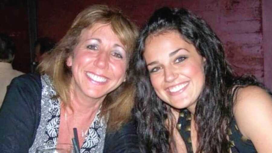 A mom and her daughter sit together at a restaurant table