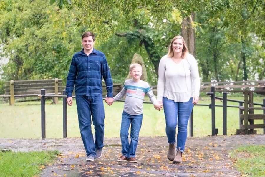 adoptive parants walk holding their son's hands