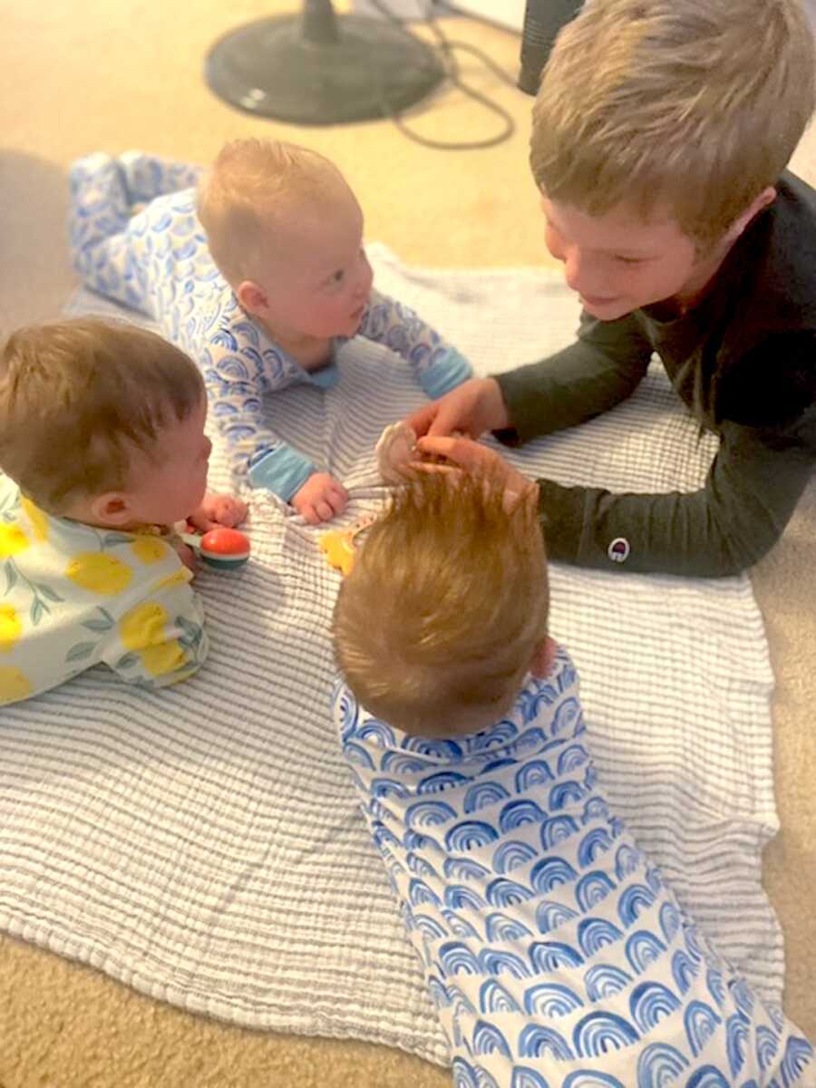 adopted son lays on his stomach with his triplet siblings