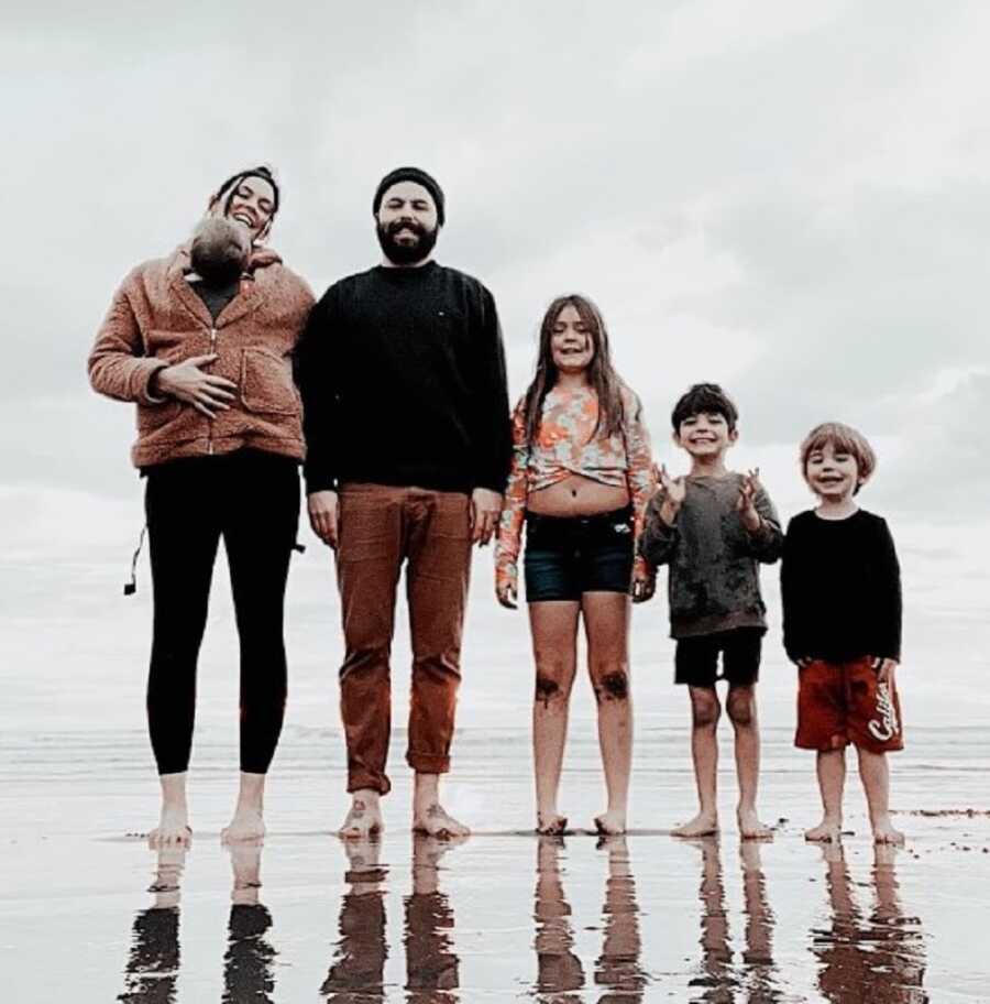 Blended family takes picture together at the beach.