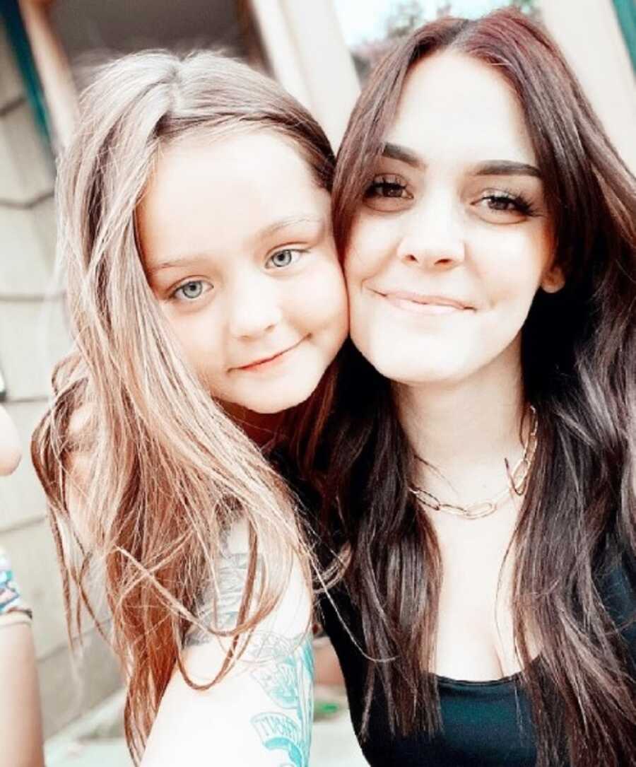 Mom and daughter take selfie with cheeks pressed together.