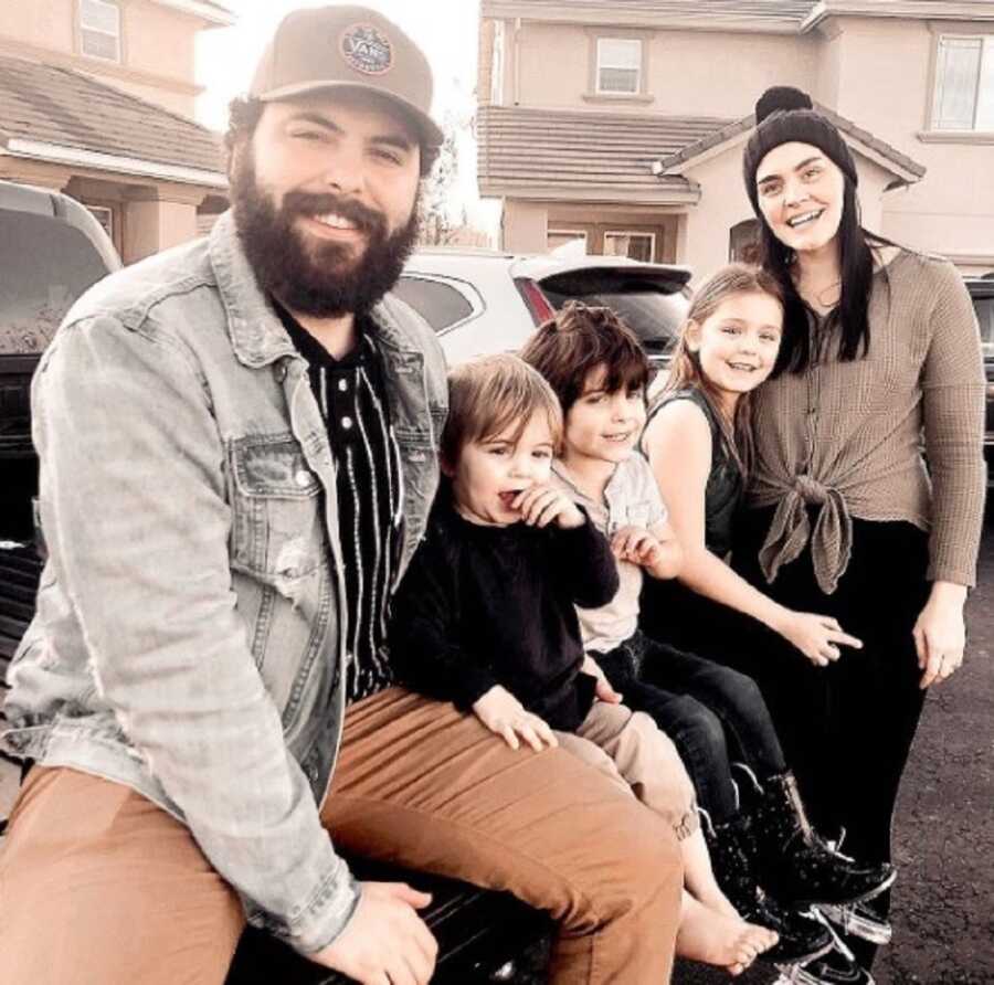 Blended family takes picture outside of their home.