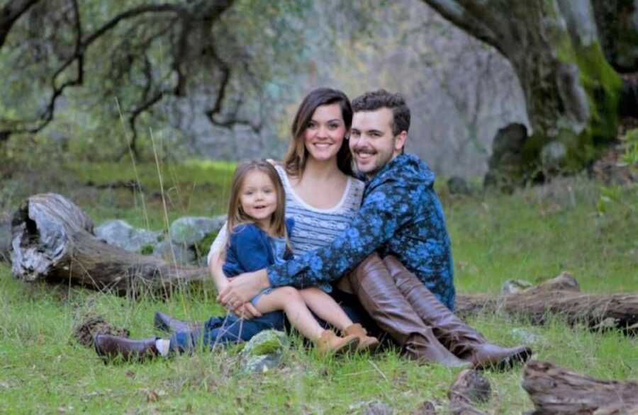 Young couple and their little girl take family picture together.