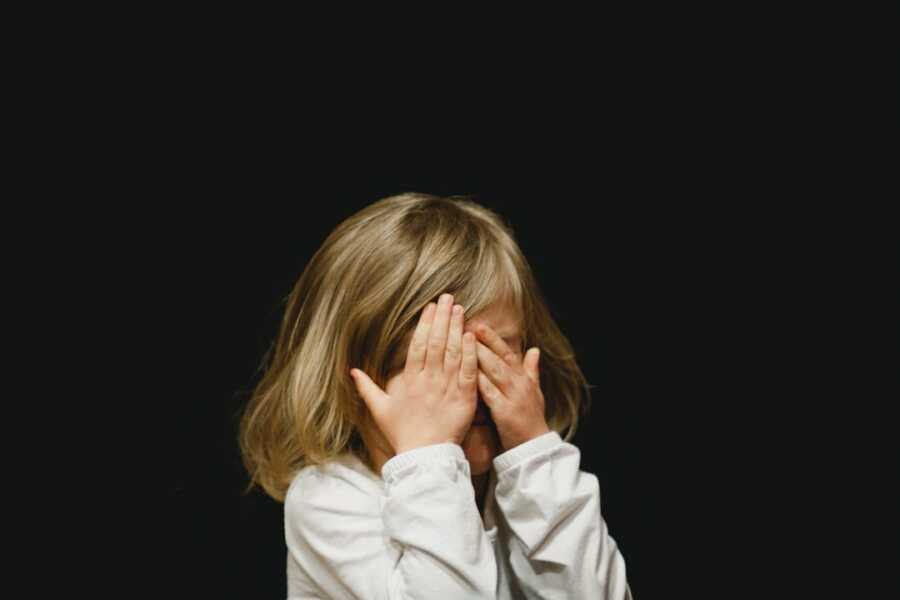 child covering their face with their hands
