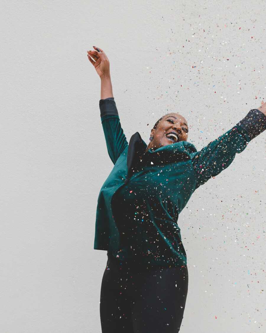 woman throws confetti in the air, smiles big