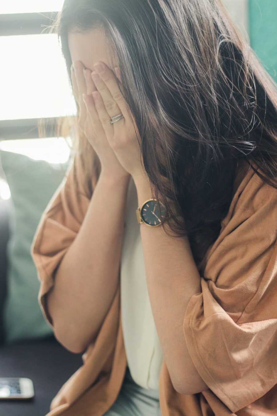 woman looks down and buries her head in her hands