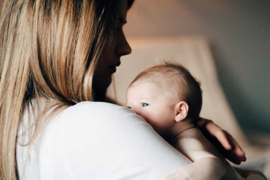 mother holds her baby on her shoulder, consoling them