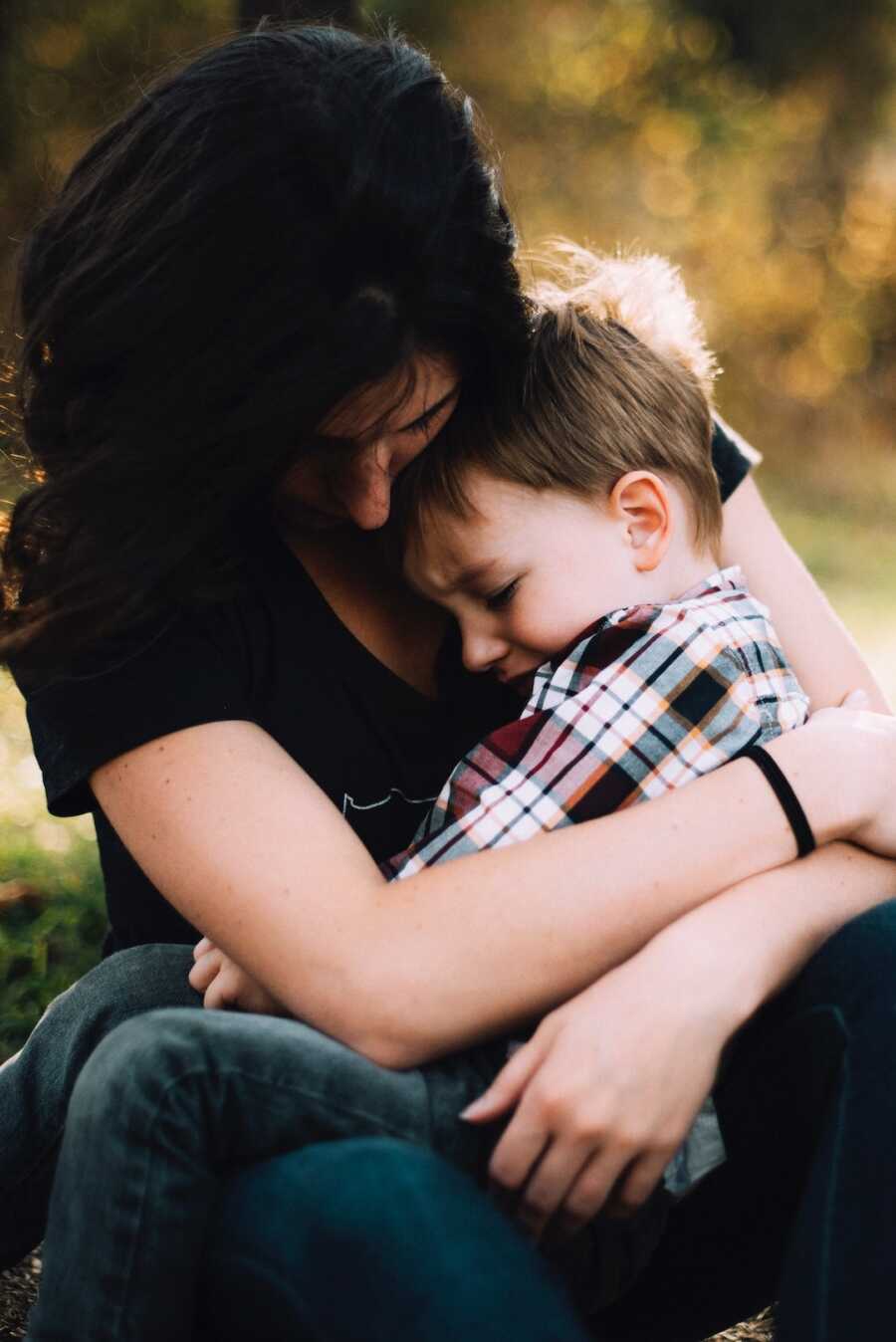 mother holds her son in her lap, embracing him