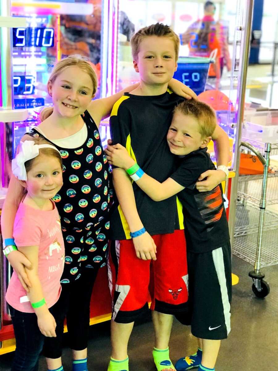 children of a blended family stand together at an arcade