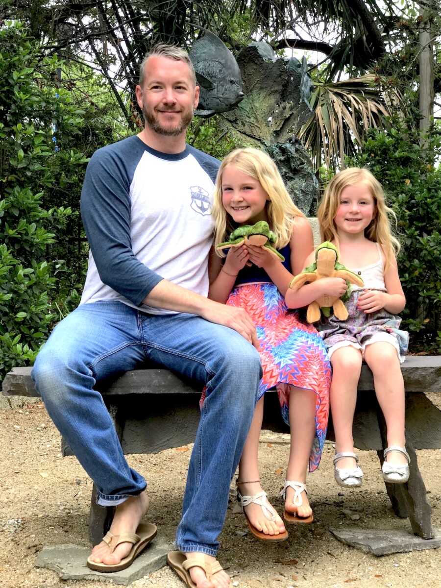 Father sits with his two daughters